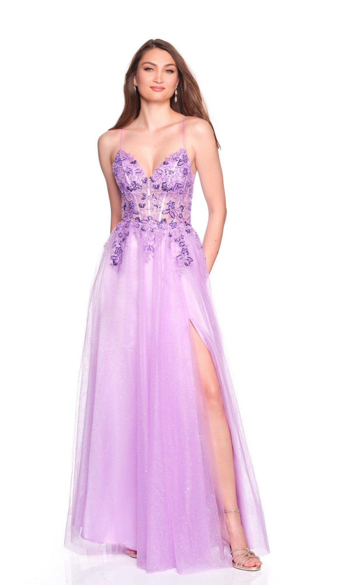 A woman wears the Dave and Johnny 12883 long prom dress in purple, featuring an embroidered corset bodice, thigh-high slit, floral embellishments, sheer details, and silver heels against a white background.